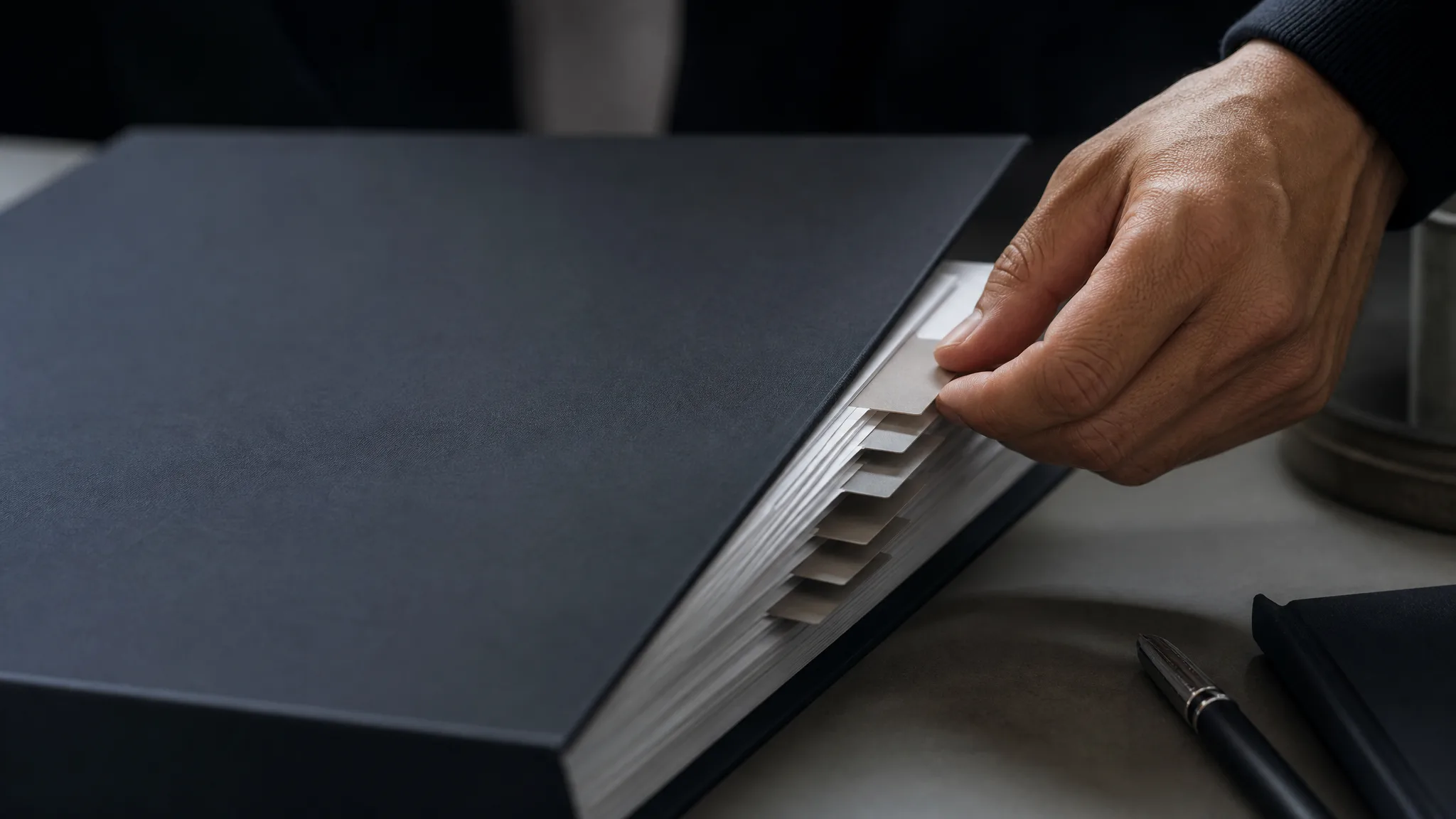 Hand aligning blank section tabs in a confidential sale binder, representing SaaS CIM preparation before buyer diligence