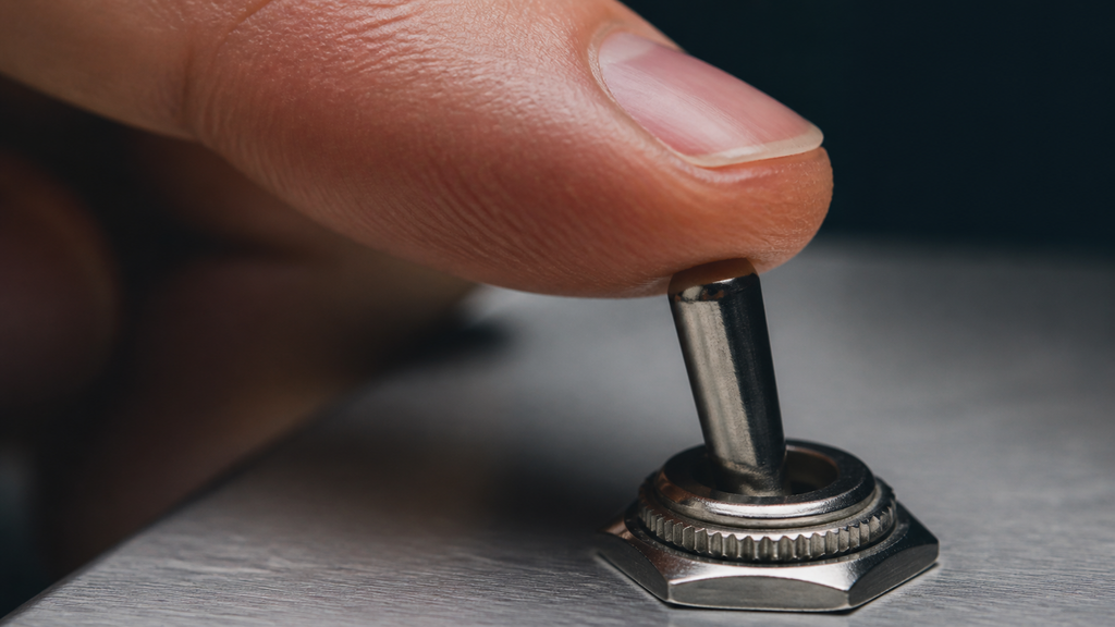 A fingertip resting on a single toggle switch, illustrating the Switch-Off Test for AI feature monetization in a SaaS valuation
