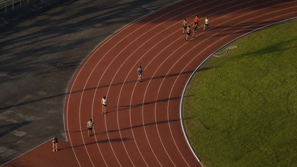 Aerial view of runners who started together now spread across a track, illustrating SaaS cohort retention over time