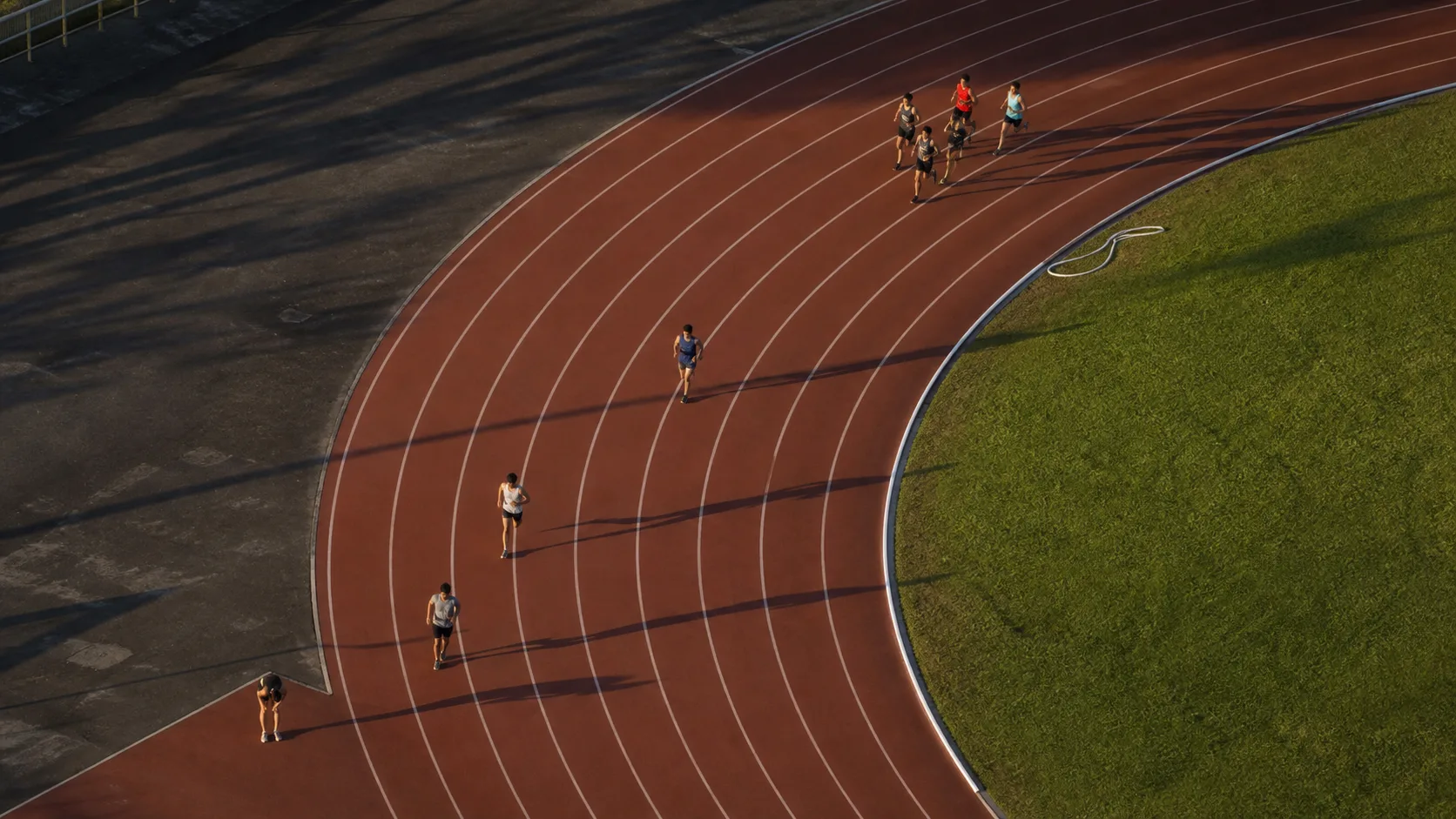 Aerial view of runners who started together now spread across a track, illustrating SaaS cohort retention over time