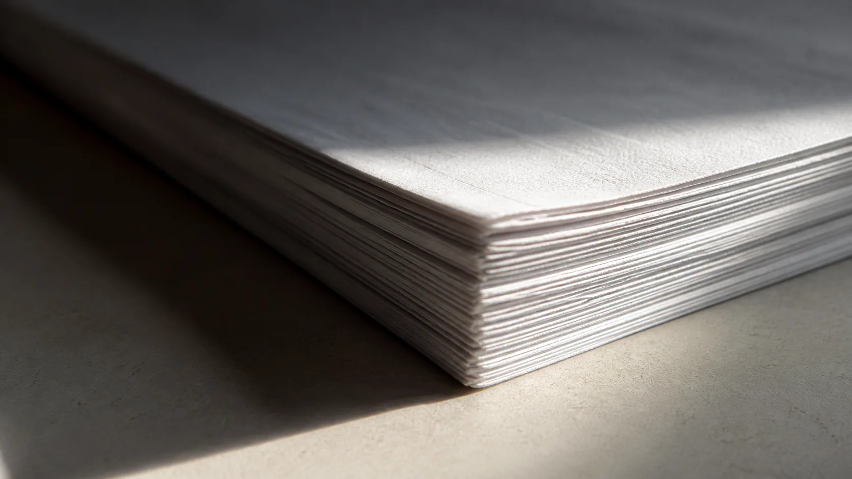 Close-up of a stack of paper documents with light falling across the edges, the diligence file that grows when a buyer asks to extend exclusivity